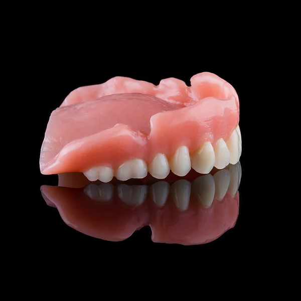 Partial denture prosthetic showing pink acrylic base with artificial teeth against black background.