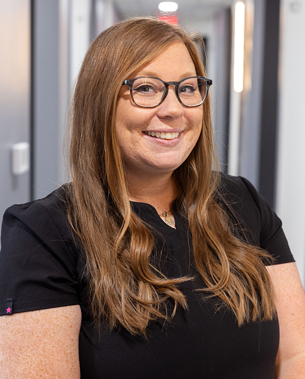 Woman wearing glasses and black shirt smiling at Hometown Dental office.