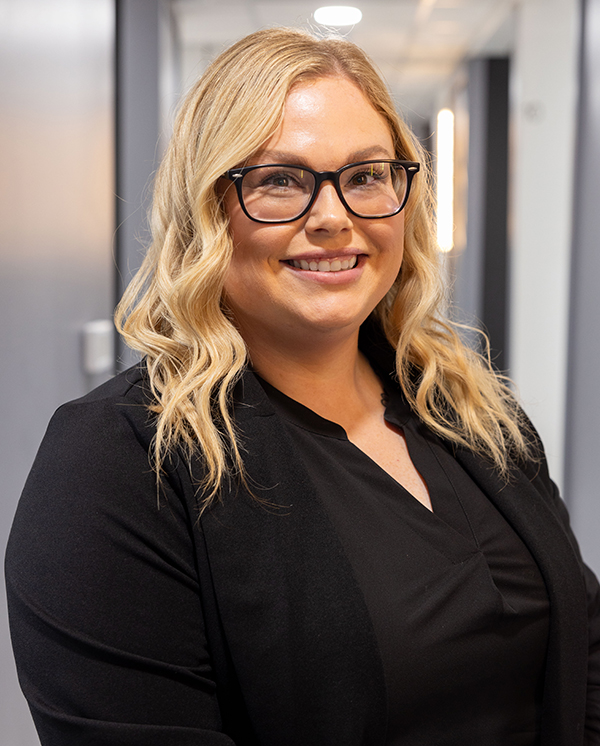 Professional woman wearing glasses and black top smiling at Hometown Dental office.