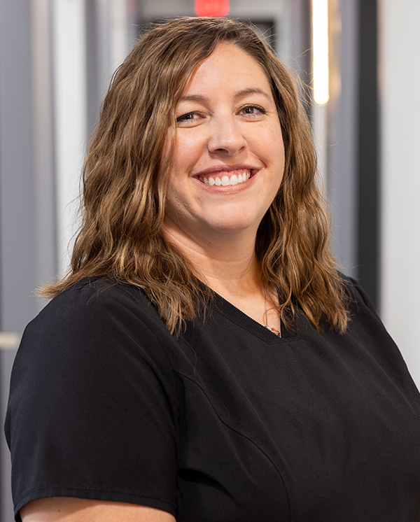 Woman smiling at camera wearing black shirt in dental office setting.