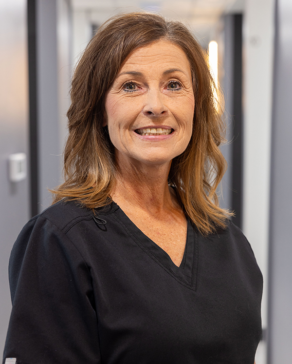 Smiling dental professional in black scrubs at Hometown Dental practice setting.