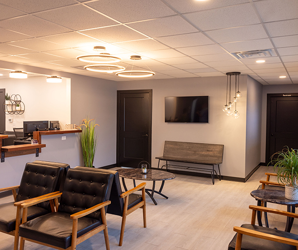 Modern dental office waiting room with comfortable seating, contemporary furniture, and warm lighting.