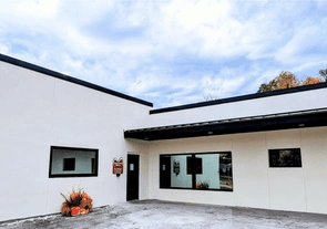 Modern white dental clinic building with dark trim and entrance, professional healthcare facility exterior.