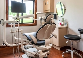 Modern dental operatory with patient chair, overhead light, and equipment in professional clinic setting.