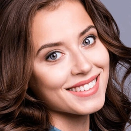 Smiling woman with wavy brown hair in professional headshot for dental practice.