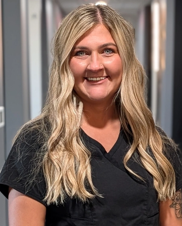 Woman smiling at camera in dental office, wearing black shirt.